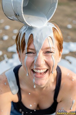 A woman in laughter gets thick silver paint poured on her head outdoors