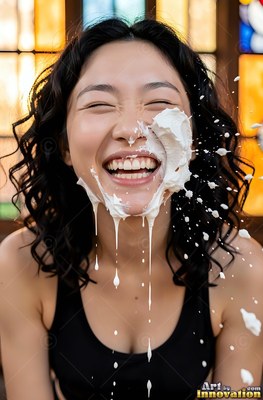 Laughing with eyes shut, a woman in a black tank top gets hit with white cream