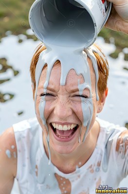 Chuckling woman looking up outdoors as thick gray paint pours on her head