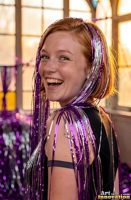 Smiling woman with purple tinsel draped in her red hair