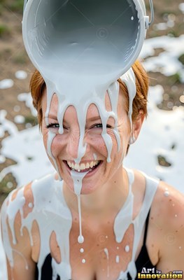 A smiling woman gets light gray paint poured on her head
