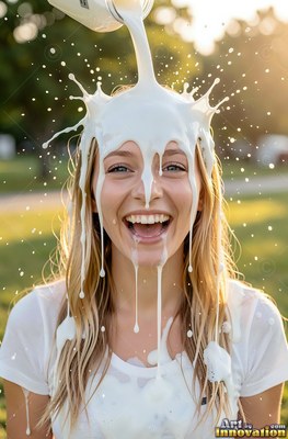 Facing forward in a sunny park, a chuckling woman gets splashing white milk poured over her head