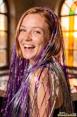 Laughing happily, a freckled woman wears shiny purple and silver tinsel in her hair