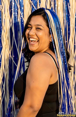 A woman laughing in a black tank top covered in blue and white streamers