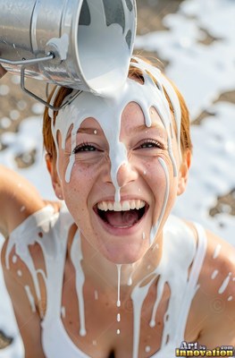 Laughing widely, a red-haired woman has thick white paint poured over her head