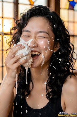 Curly dark hair frames a laughing woman smeared with cream by a sunny window