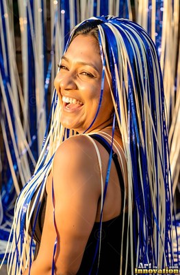 Turned over her shoulder outside, a giggling woman is draped in blue and white ribbons