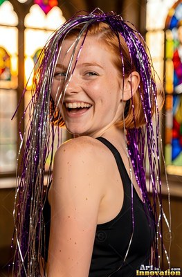 A smiling red-haired woman wearing purple and silver tinsel over her head
