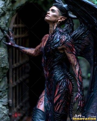 A demon woman with wings with pointed ears looks up outside a dark stone doorway