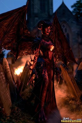 Standing upright in a dark graveyard, a horned woman spreads wide leathery wings