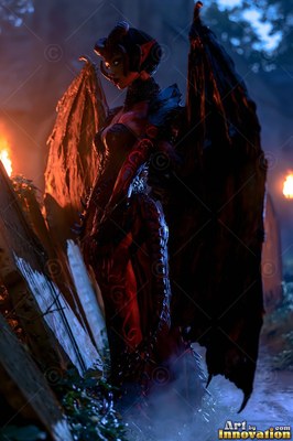 In a dark garden by torchlight, a horned winged woman stands near tombstones