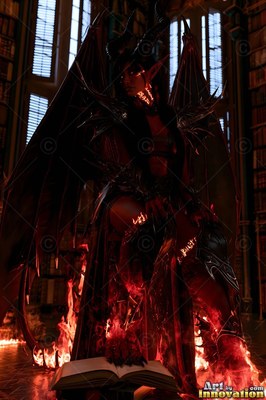 Sitting above open flames, a horned demon woman with wings rests her claw on a book