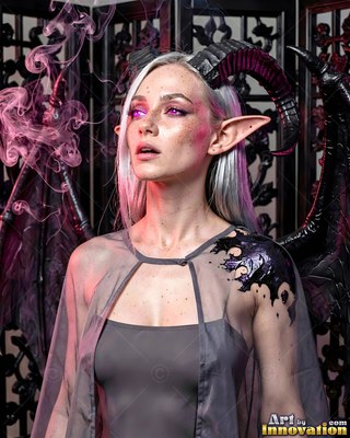 A woman with black horns and wings looks up beside drifting pink smoke