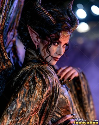 A horned sharp-eared woman looks back over her shoulder in a bronze gown