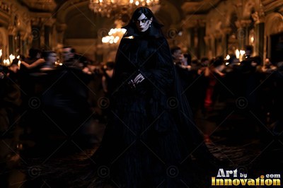 A fair woman stands in a black cloak before a dark ballroom lit by warm chandeliers