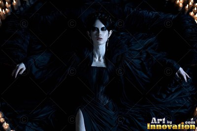 A light-skinned woman lies back in black fabric ringed by small candlelight