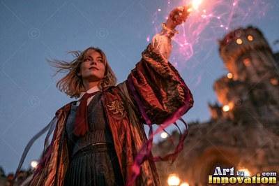 A young sorceress in scarlet and gold robes throws up a shield of light beneath the floating candles of the great hall