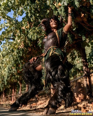Reaching for grapes, a woman with horns with black furry legs stands in a vineyard