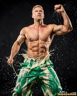 Shirtless muscular man in green pants splashed with white liquid