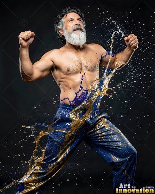 Flexing with fists raised, a bearded man is splashed with blue and gold liquid