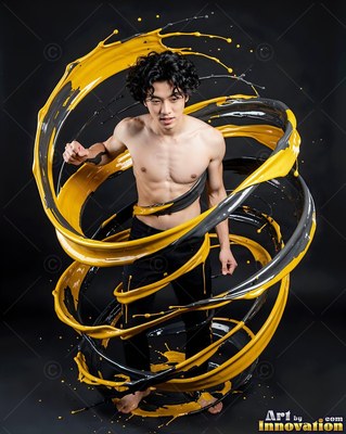 Standing in a dark studio, a shirtless man is circled by swirls of yellow paint