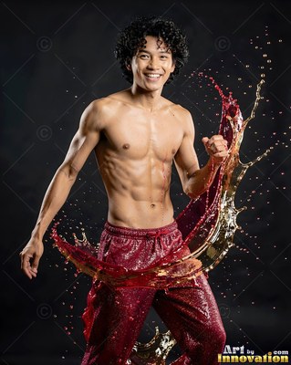Wet red sweatpants on a shirtless man smiling as red and gold liquids splash in a dark studio
