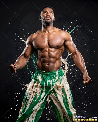 Flexing in a dark studio, a shirtless man is splashed with white and green paint