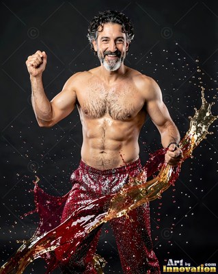 Smiling with raised fist, a shirtless man swings splashes of amber liquid