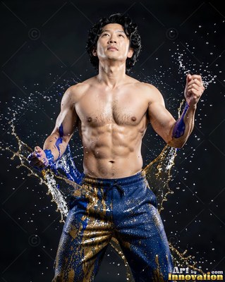 A shirtless man flexes his arms as water splashes past his blue pants