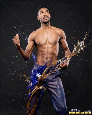 Looking up with fists clenched, a shirtless man is splashed by blue and gold liquid