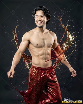 Smiling shirtless man in red pants with splashing gold liquid behind him