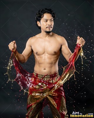 A shirtless man pulls a wide splash of red and gold liquid upward in clear studio light