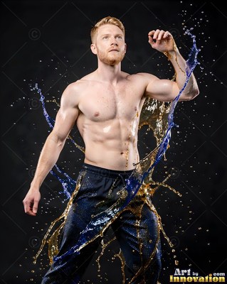 In a dark studio, a shirtless man dodges splashes of blue and gold water