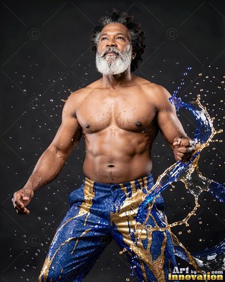 Looking upward, a shirtless bearded man stands as blue and gold water splashes around him
