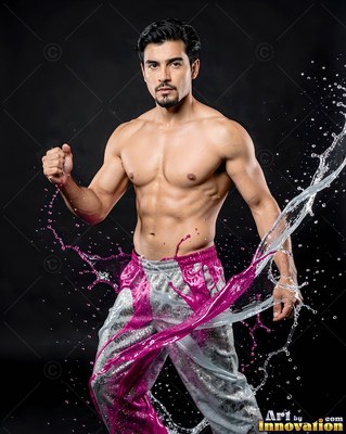 In a dark studio, a shirtless man poses as pink liquid and clear water splash