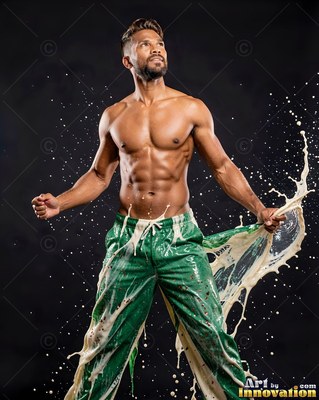 Shirtless man in green pants splashed with creamy liquid