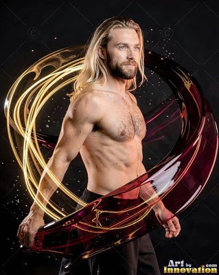 A shirtless blond man turns as ribbons of gold and red liquid swirl around him