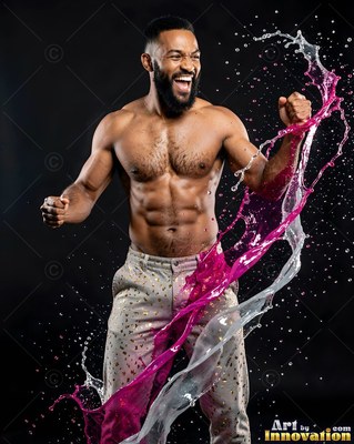 A shirtless man cheers as pink water splashes around him