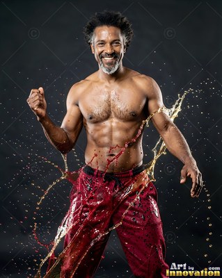 Standing front and center in a studio, a smiling man has water splashing at his hips