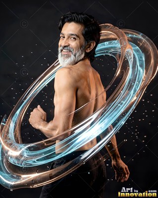 A smiling man with a white beard poses shirtless inside rings of water against a dark studio background