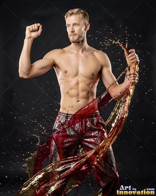 A shirtless blond man poses as red and gold water splashes around him