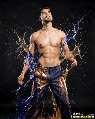 Shirtless man splashed with blue and gold liquid on dark background