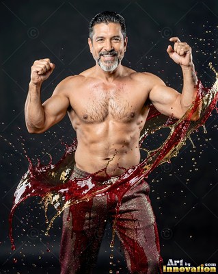 A shirtless man raises his fists as red liquid splashes by