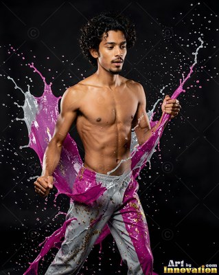 In a dark studio, a shirtless man pulls pink and silver paint around his waist