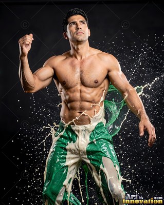 A muscular shirtless man splashed with green and white paint