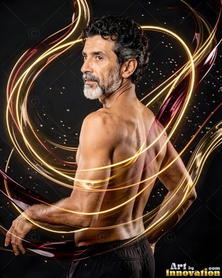 Turned three-quarters in a dark studio, a shirtless man encircled by gold light loops
