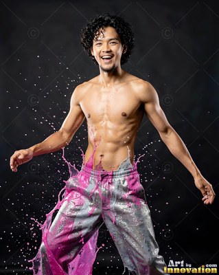 Shirtless smiling man with pink paint splashing over his shiny pants
