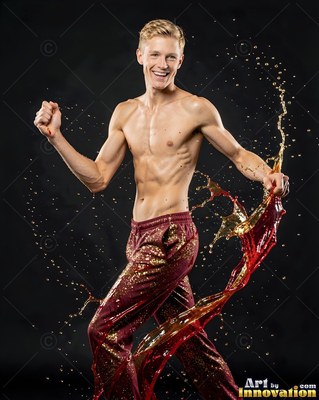 Posing shirtless, a smiling man struts as splashes of amber liquid curl around his legs