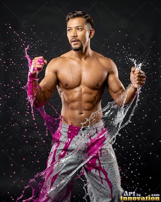 A muscular man raises his fists as pink and clear water splashes around him