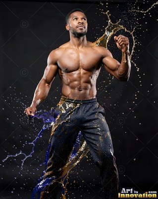 In a dark studio, a muscular man stands splashed with blue and gold liquid